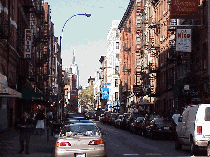 Top left picture you see a restaurant worker standing outside to welcome people inside. Center right picture you see a long shot of Mulberry Street.  If you zoom in you can see the Empire State Building in the distance.