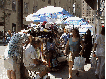 Center right picture you see a sidewalk nearby where vendors are selling their merchandise under umbrellas.