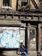 A man relaxing near a graffiti covered gate